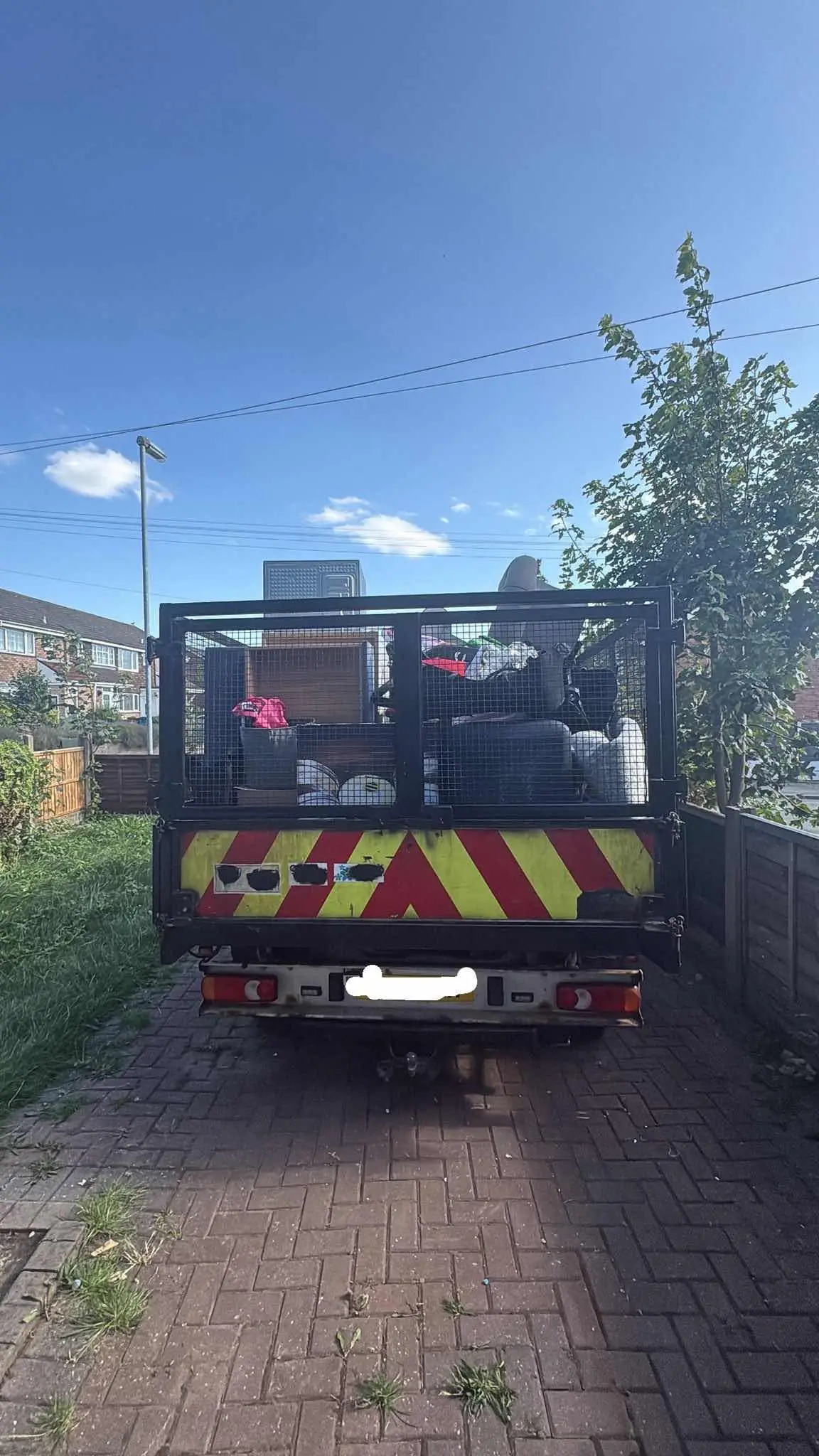 A caged tipper truck loaded with old furniture and appliances