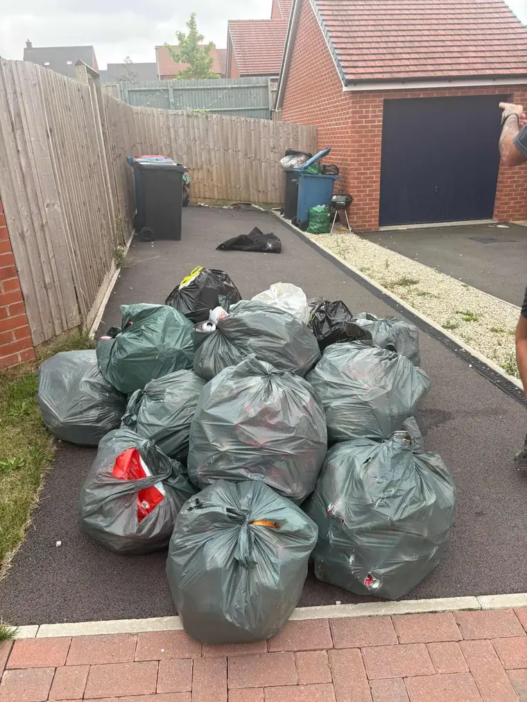 A tidy pile of bagged household waste collected on a driveway ready for removal